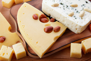 Various cheeses, apple, dried apricots, peanuts, walnuts, pears, berries, honey, jam, cheese with a mold on a wooden board in the style of pop art and retro style, Christmas cheese, festive dinner