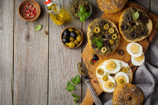 Sandwich  from bread or bagels with tapenade, olives and boiled chicken eggs on an old wooden background. Selective focus. Top view. Copy space.