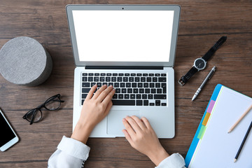 Young woman using laptop with blank screen at table