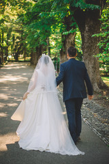 The bride and groom walk in the park.