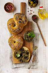 Tapenade, traditional Provence dish with black and green olives, basil and Bagels on light  wooden table background. Selective focus. Top view.