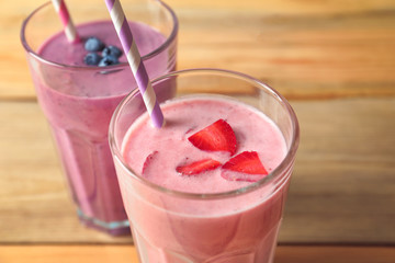 Glasses with yummy smoothie on wooden table, closeup