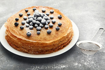 Pancakes with blueberries and powdered sugar on grey wooden table