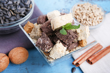 Tasty slices of halva in bowl on wooden table