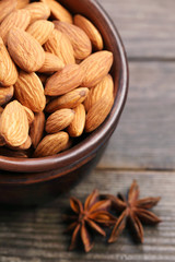 Almonds in bowl with star anise on wooden table
