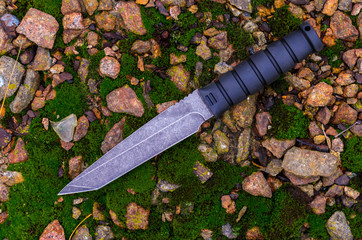 A military knife on the autumn ground. Autumn mood.