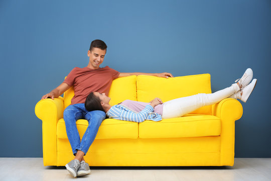 Young Couple On Yellow Sofa Near Color Wall