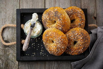 Bagels in wooden rustic box  with  textile napkin on  old wooden background. Selective focus. Top...