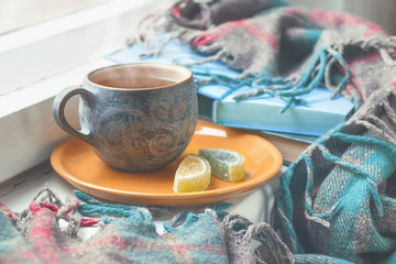 Cozy morning at home. A cup of tea, a blanket, old books and glasses on the windowsill, selective focus.