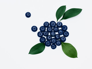 Blueberries and leaves isolated Bright green leaves and handful of blueberries are lying on a white background Flat lay Modern minimalist photo template