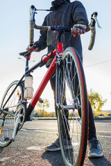 Naklejka premium Man stands with road bike. Bicycle wheel close-up