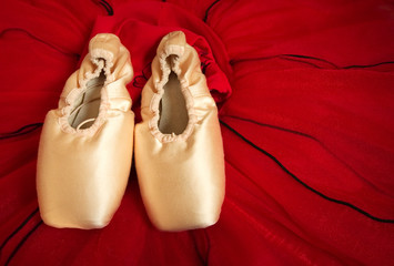 Ballet shoes over red dance dress. Concept closeup imagine for academy, school, classes and practicing.