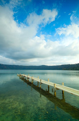Panoramic view from the shore of the volcanic lake of Castel Gandolfo, famous for being papal summer residence. Gangway over water closeup