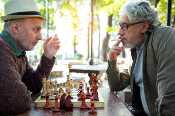 Mature male friends entertaining with chess game