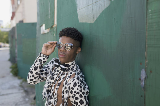 Portrait Of Young Man In Spotted And Torn Shirt Standing Against Wooden Wall