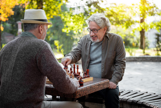 Cheerful senior men playing chess together outdoor