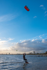 Kite surfer s'eloignant sur la mer pendant un coucher de soleil a Melbourne, Australie