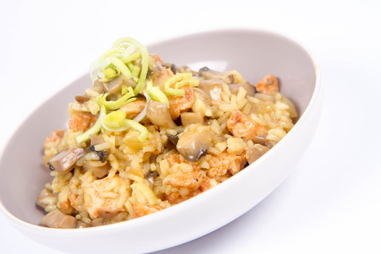Risotto with mushrooms and chicken decorated with leek on a white background
