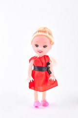 Doll in red dress on white background. Beautiful smiling baby doll with blond hair isolated on white background. Cute gift for child.