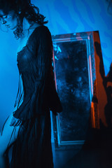 implied nudity white female model black dress veil red blue shadow mirror background curly hair