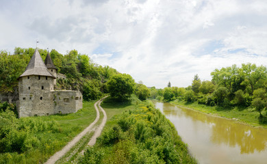 Fototapeta na wymiar Old castle with road and river on cloudy sky background