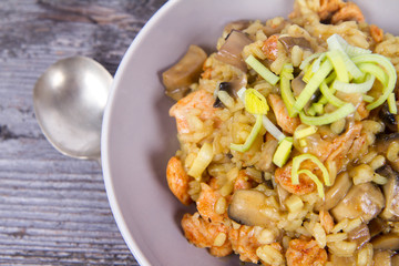 Risotto with mushrooms and chicken decorated with leek on a wooden background