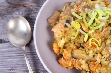 Risotto with mushrooms and chicken decorated with leek on a wooden background