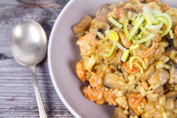 Risotto with mushrooms and chicken decorated with leek on a wooden background