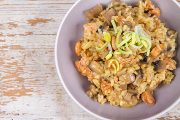 Risotto with mushrooms and chicken decorated with leek on a wooden background