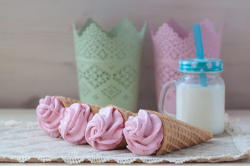 Pink raspberry flavour marshmallows or zephyr with milk on the wooden background