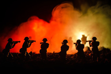 Fototapeta premium War Concept. Military silhouettes fighting scene on war fog sky background, World War Soldiers Silhouettes Below Cloudy Skyline At night. Attack scene. Armored vehicles. Selective focus