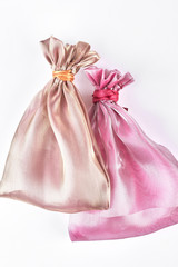 Beige and pink jewelry bags. Two silk sacks for keeping jewelry, isolated on white background. Pouch for girls gold.