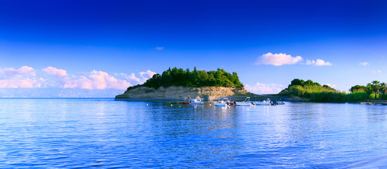 Beautiful summertime panoramic seascape. View of the cliff called Small D`Amour Canal, into the crystal clear azure sea bay and distant albanian coast. Boats mooring. Sidari. Corfu. Greece. - obrazy, fototapety, plakaty