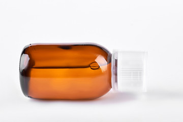 Fototapeta na wymiar Antipyretic syrup in brown bottle. Cough syrup in glass brown bottle lying on white background. Mixture for cough treatment.