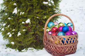 Colored Christmas-tree toys in a vintage basket on the snow