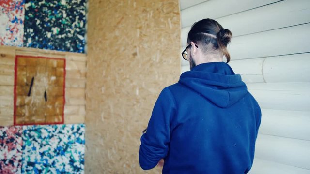 Young man is throwing axes at the target