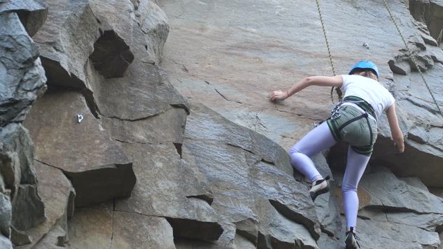 A female rock climber climbs up a rock. Learning to climb. Rock, girl, mountaineering