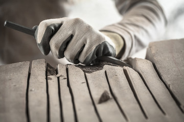 Particolare delle mani dell'artista che lavora il marmo con martello e scalpello