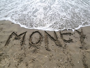 word MONEY on the sand and wave that is erasing the text symbol