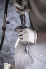 Artista che scolpisce il marmo con un martello pneumatico