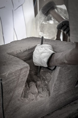 Particolare delle mani dell'artista che lavora il marmo con martello e scalpello