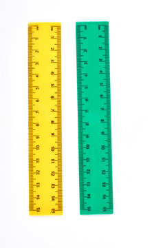 Yellow and green plastic rulers. Two fifteen centimeters rulers for measuring in school, isolated on white background. Vertical image of plastic rulers.