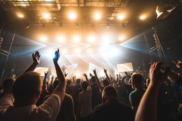 silhouettes of concert crowd in front of bright stage lights