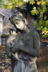 Fototapeta na wymiar The stone Girl on Tomb from the autumn old Prague Cemetery, Czech Republic