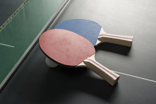 Ping Pong Paddles on Table, both on same side, harsh lighting