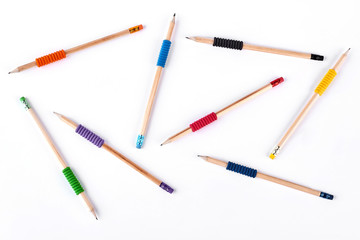 Fototapeta premium Background of different pencils. Simple pencils with colorful elastic bands chaotically placing on white background, top view.