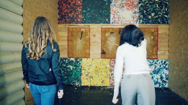 Two girls throw axes at the target