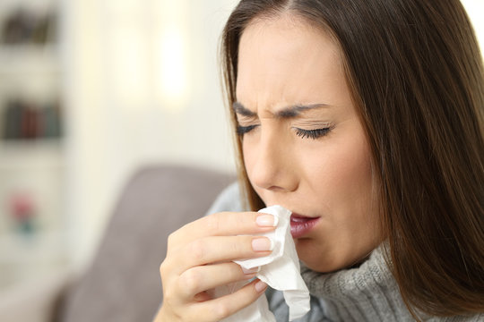 Ill woman coughing using a tissue