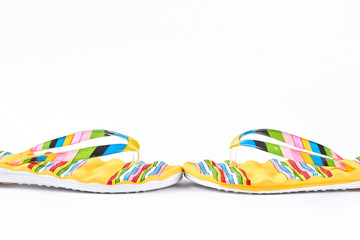 New colorful flip flops on white background. Yellow slippers with multicolored stripes on white background. Summer vacation concept.