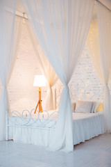 Fototapeta na wymiar Bedroom in soft light colors. Big comfortable double bed in elegant classic interior